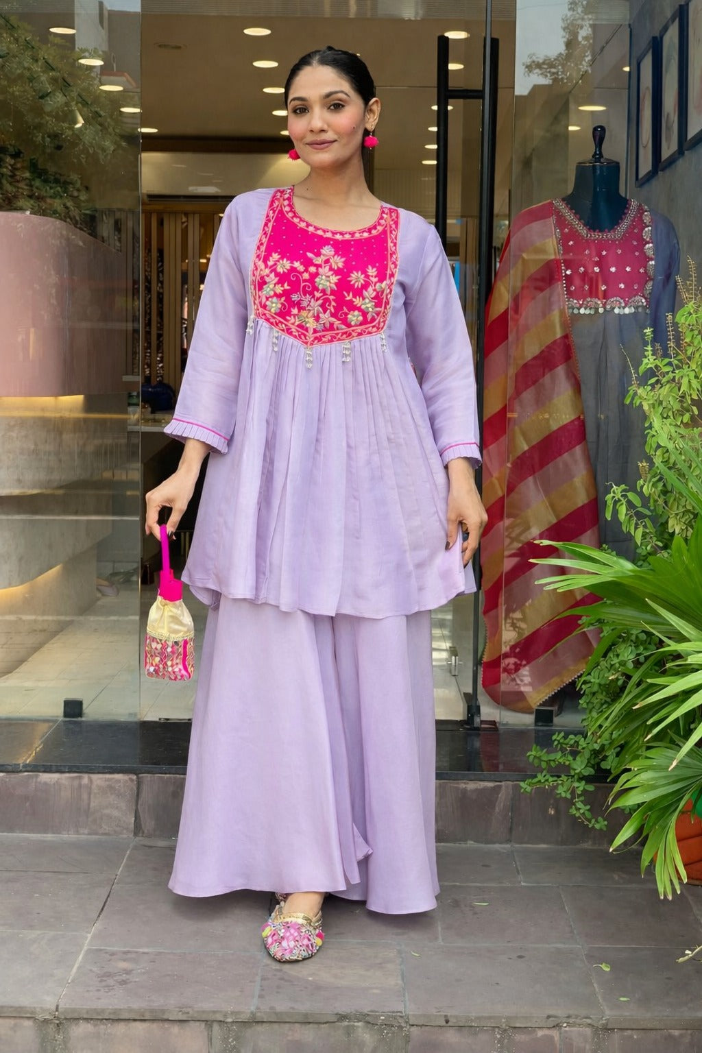 Elegant lavender kurta set with a striking magenta yoke, detailed floral embroidery, fine zari work, and pearl tassels for a rich festive look.